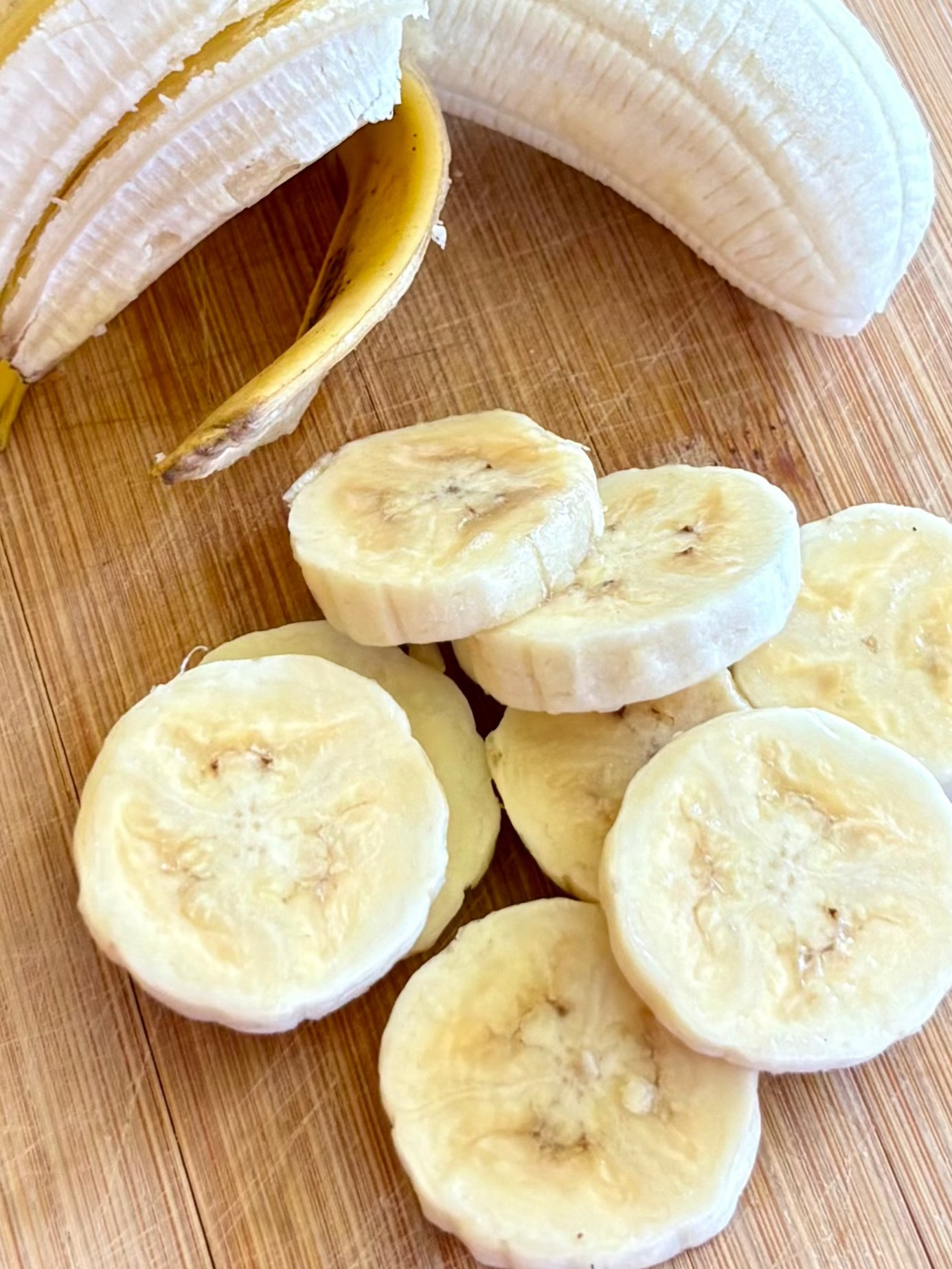 Sliced bananas on a wooden cutting board with a decorative glass table